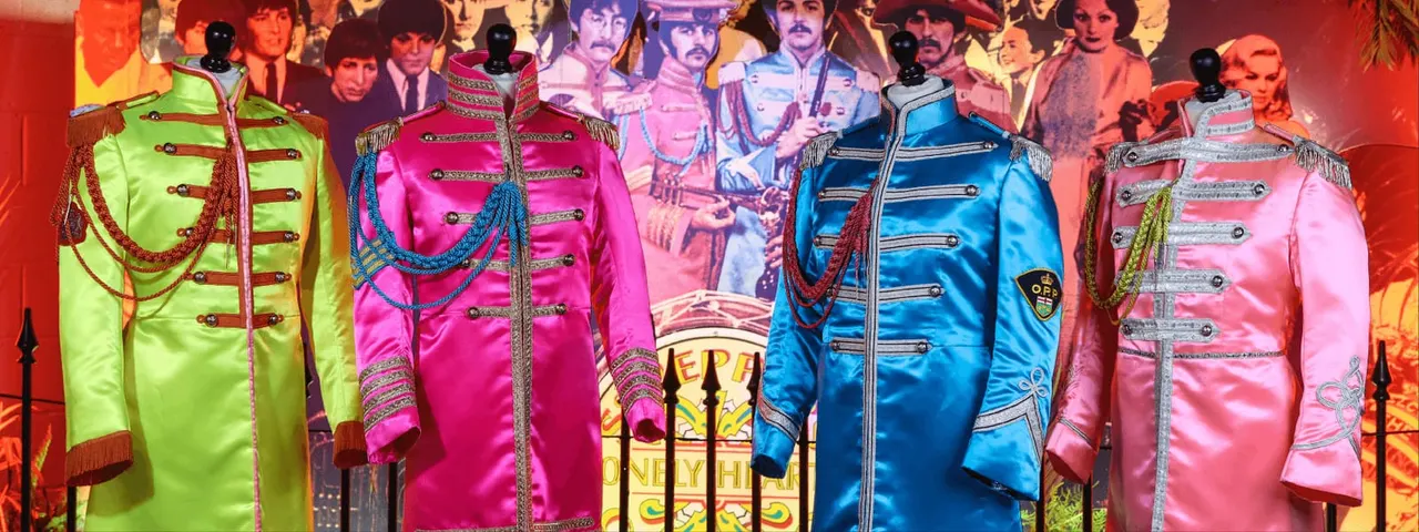 Colourful military-style jackets on mannequins displayed against a backdrop of 1960s musicians.