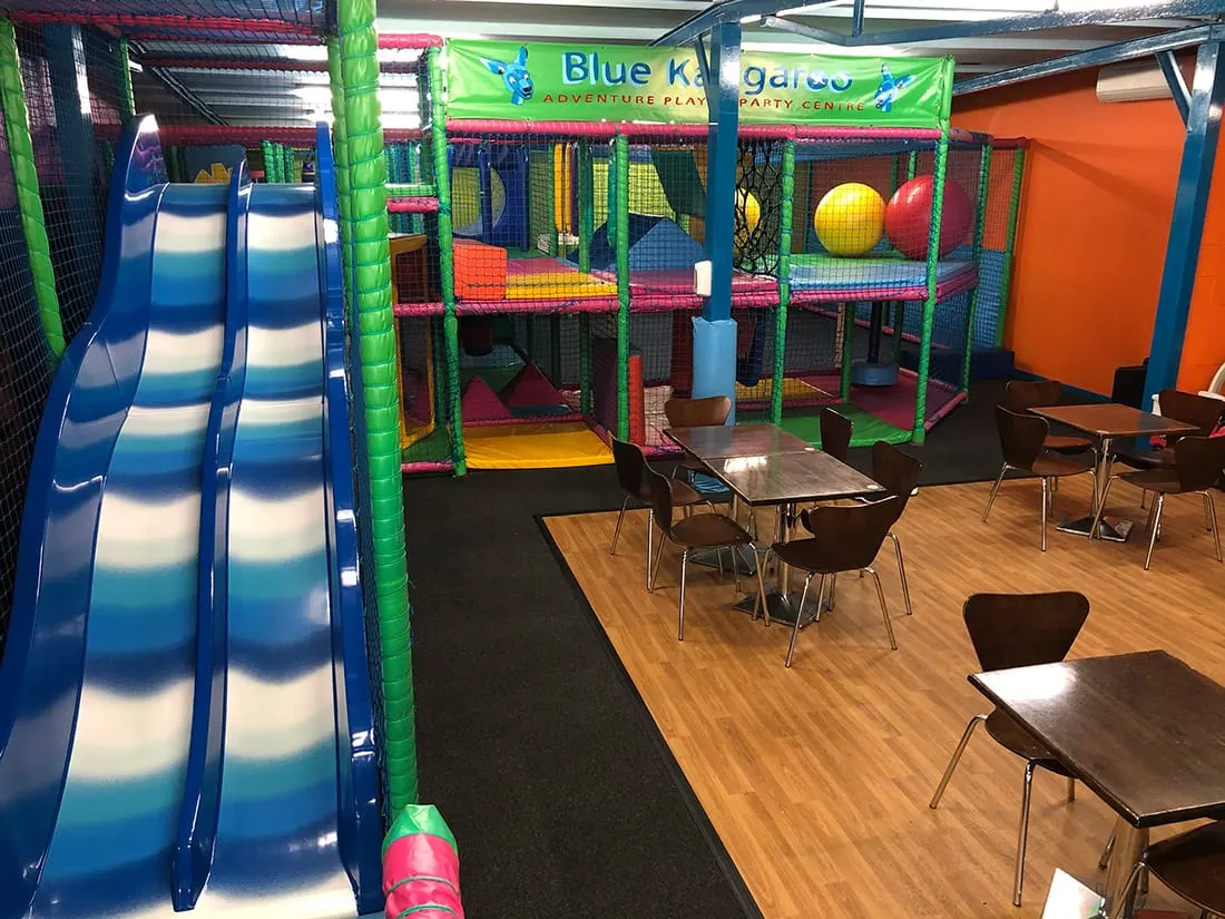 Indoor play area with colourful climbing structures, slides and ball pits, plus dining tables for supervising adults.