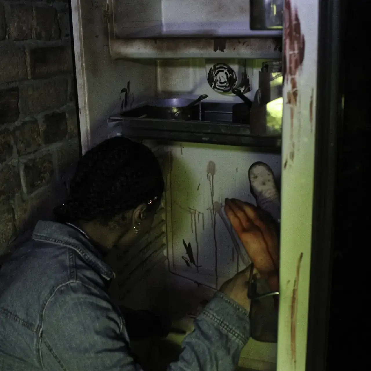 A person examines a futuristic control panel and machinery inside a narrow escape room chamber.