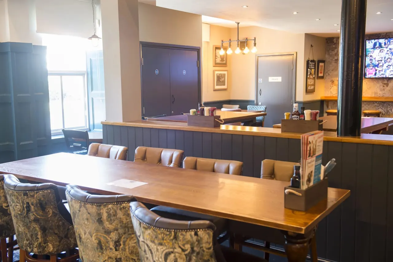 Interior of a games lounge with pool tables, bar seating, and casual dining furniture.