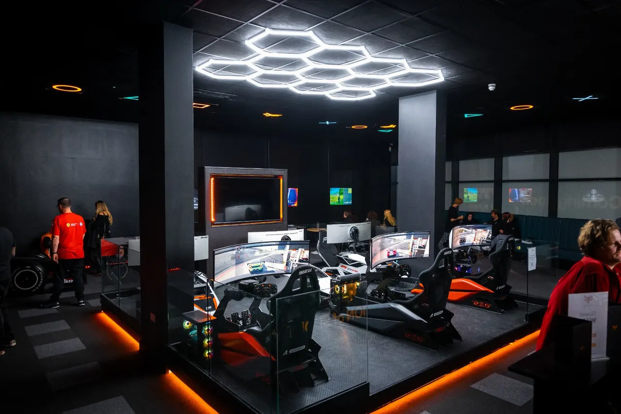 Modern indoor racing simulator venue with multiple racing cockpits, large screens, and neon lighting, visitors of various ages using and observing the equipment.