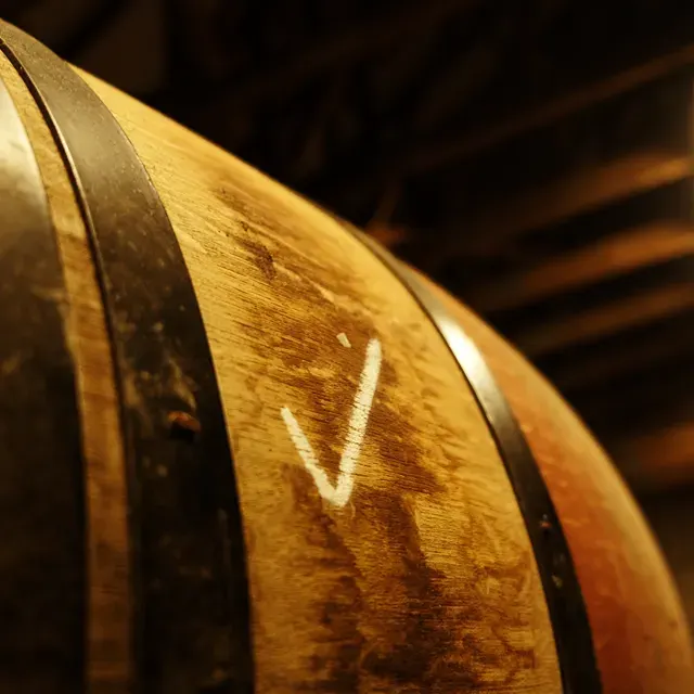 Close-up of wooden barrel with metal bands and maker's mark at a distillery.