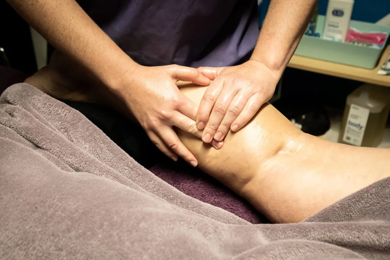Therapist performing a massage on a client's leg during a wellness treatment session.