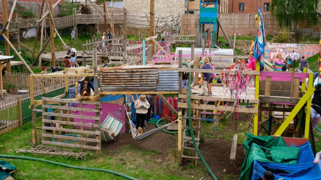 Children playing on wooden structures, slides and climbing equipment at an outdoor adventure playground.
