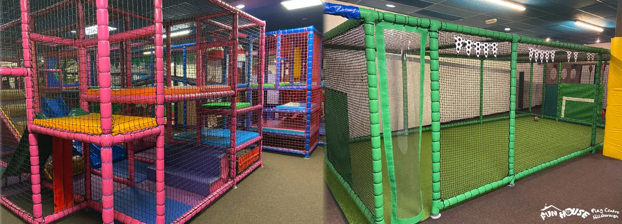 Indoor play centre with colorful soft play structures including pink and blue climbing frames on the left and a green netted enclosure on the right.