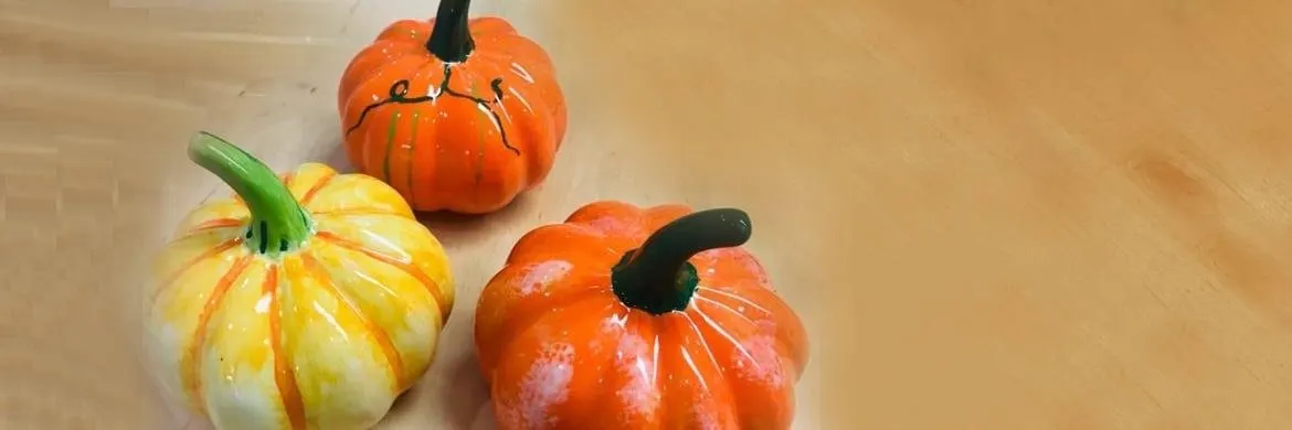 Three decorative painted gourds in orange and yellow on a wooden surface.