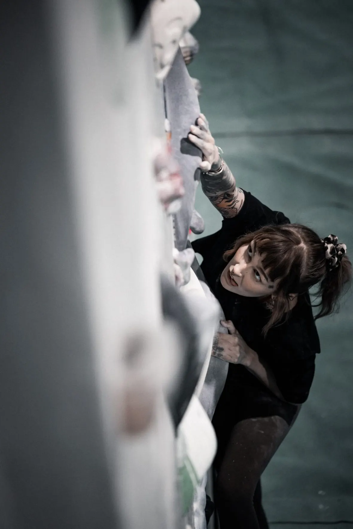 Person ice climbing on an indoor wall, gripping the frozen surface with wrapped hands.