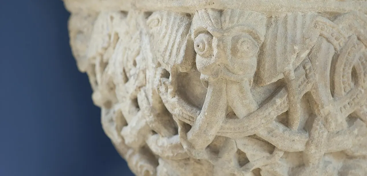 Close-up of carved stone architectural detail featuring stylised animal heads in relief.