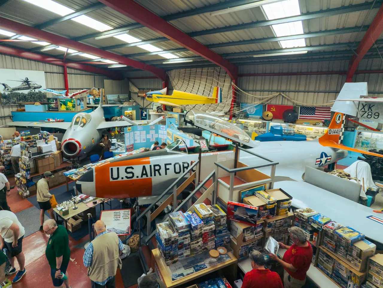 Visitors exploring a hangar filled with vintage aircraft, scale models, and aviation memorabilia at an aerospace museum.