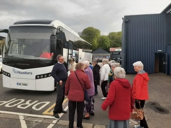 A group of visitors boarding a coach bus for a guided tour departure.
