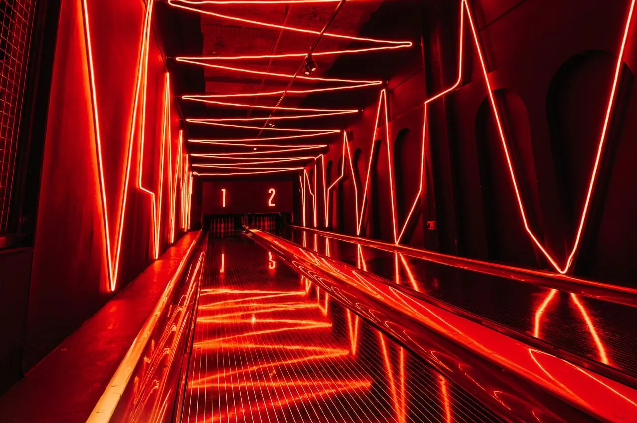 Bowling alley lane with bright red neon lighting and numbered pins visible at the far end.