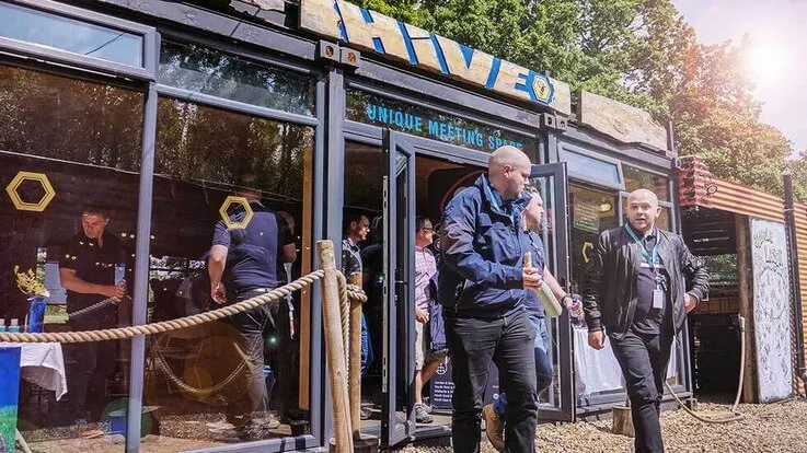 Visitors and staff gather outside a venue building with blue signage during what appears to be an opening or special event.