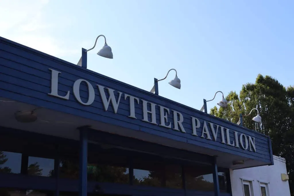 The Lowther Pavilion building exterior with blue signage and wall-mounted lamps against a clear sky.