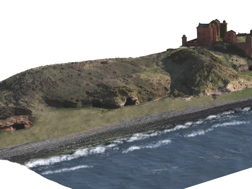 Shingle beach with waves, moss-covered rocks and a ruined castle on a grassy headland.