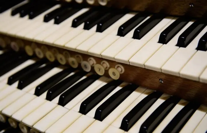 Close-up of an organ's two manual keyboards with black and white keys and wooden stops.