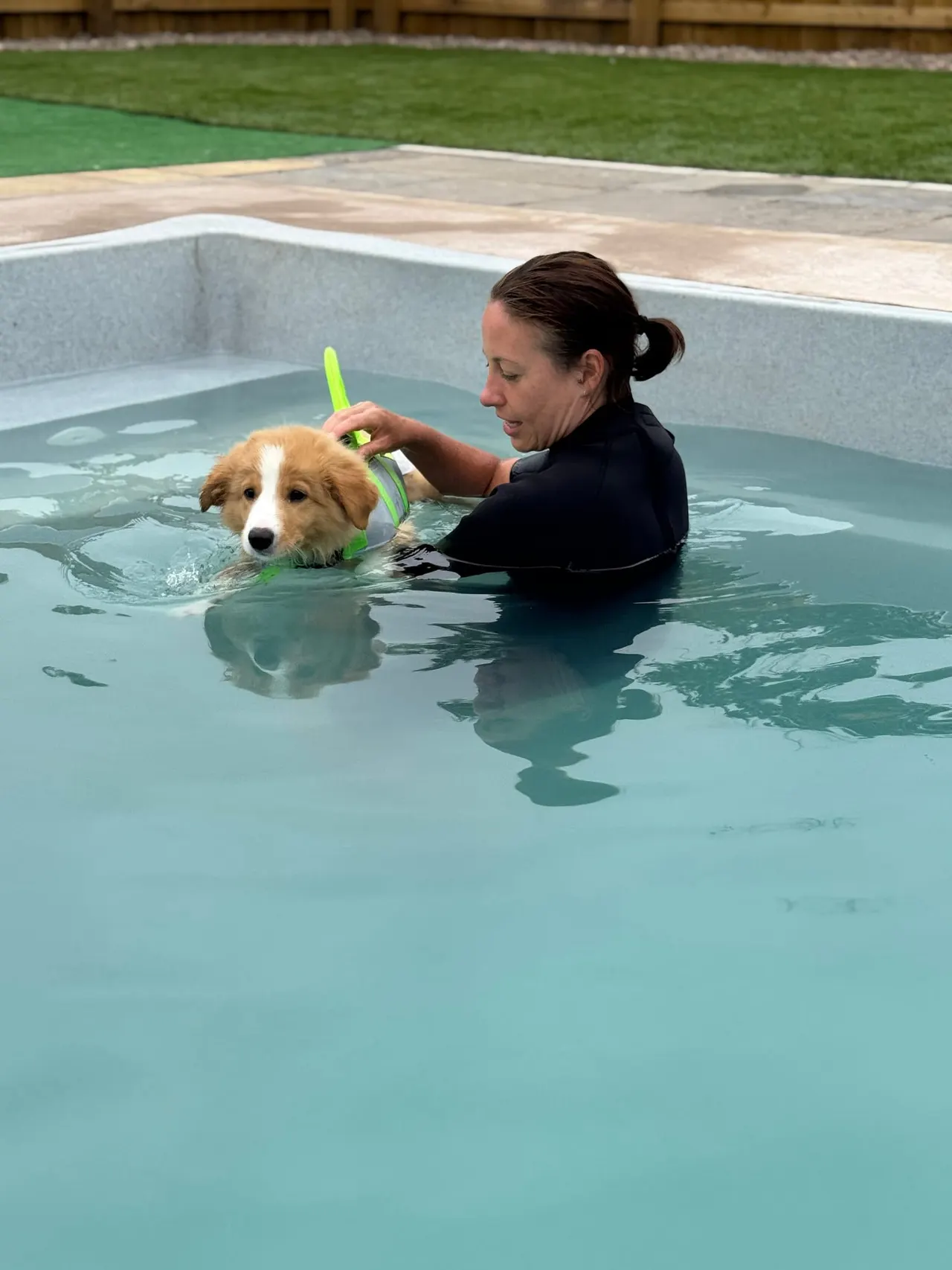 Woman in water with a dog during a hydrotherapy or swimming session in a pool.