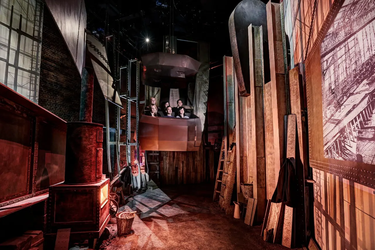 Visitors ride a themed attraction through an industrial-styled set depicting a ship's interior, with red-lit metal structures and period scenery.