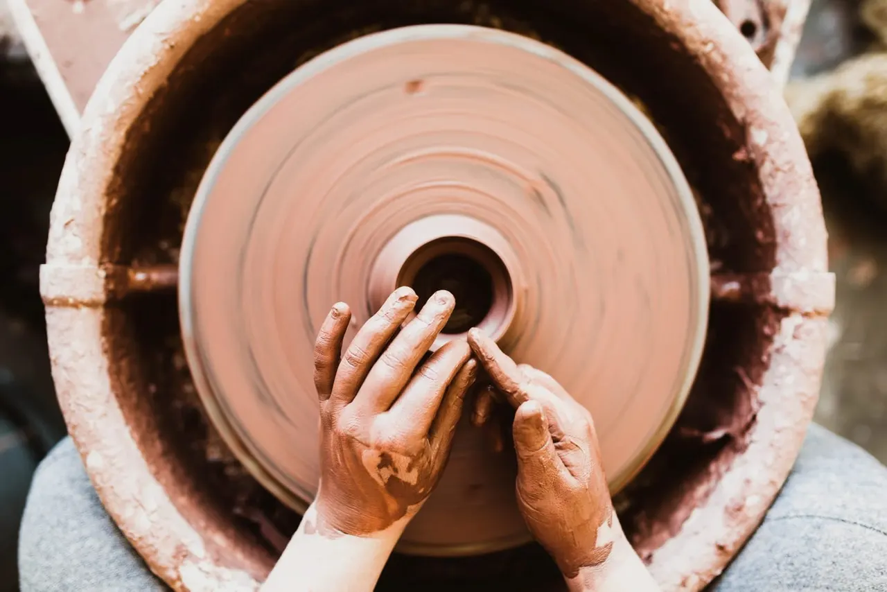 Hands shaping clay on a potter's wheel during a pottery session.