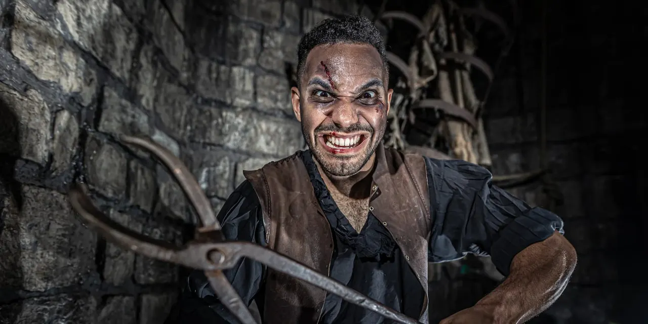 Actor portraying a menacing character with theatrical makeup inside a dungeon setting.