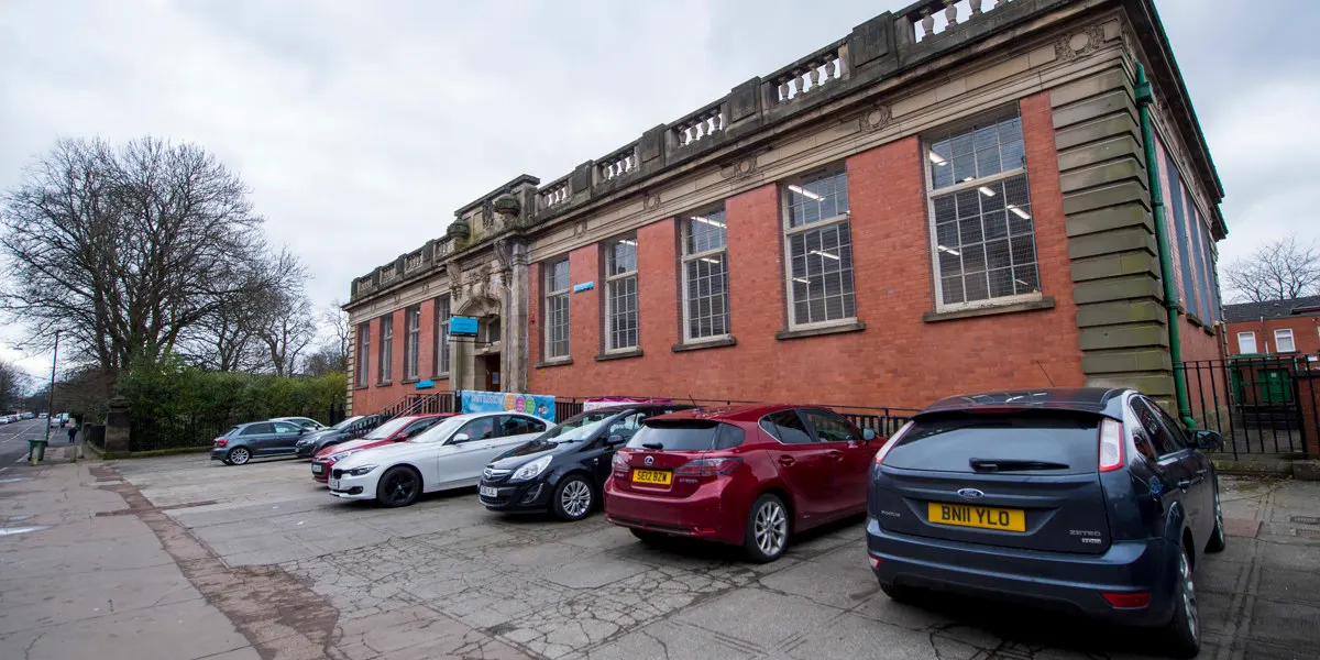 Cars parked outside a brick Victorian building with large windows and decorative stonework.
