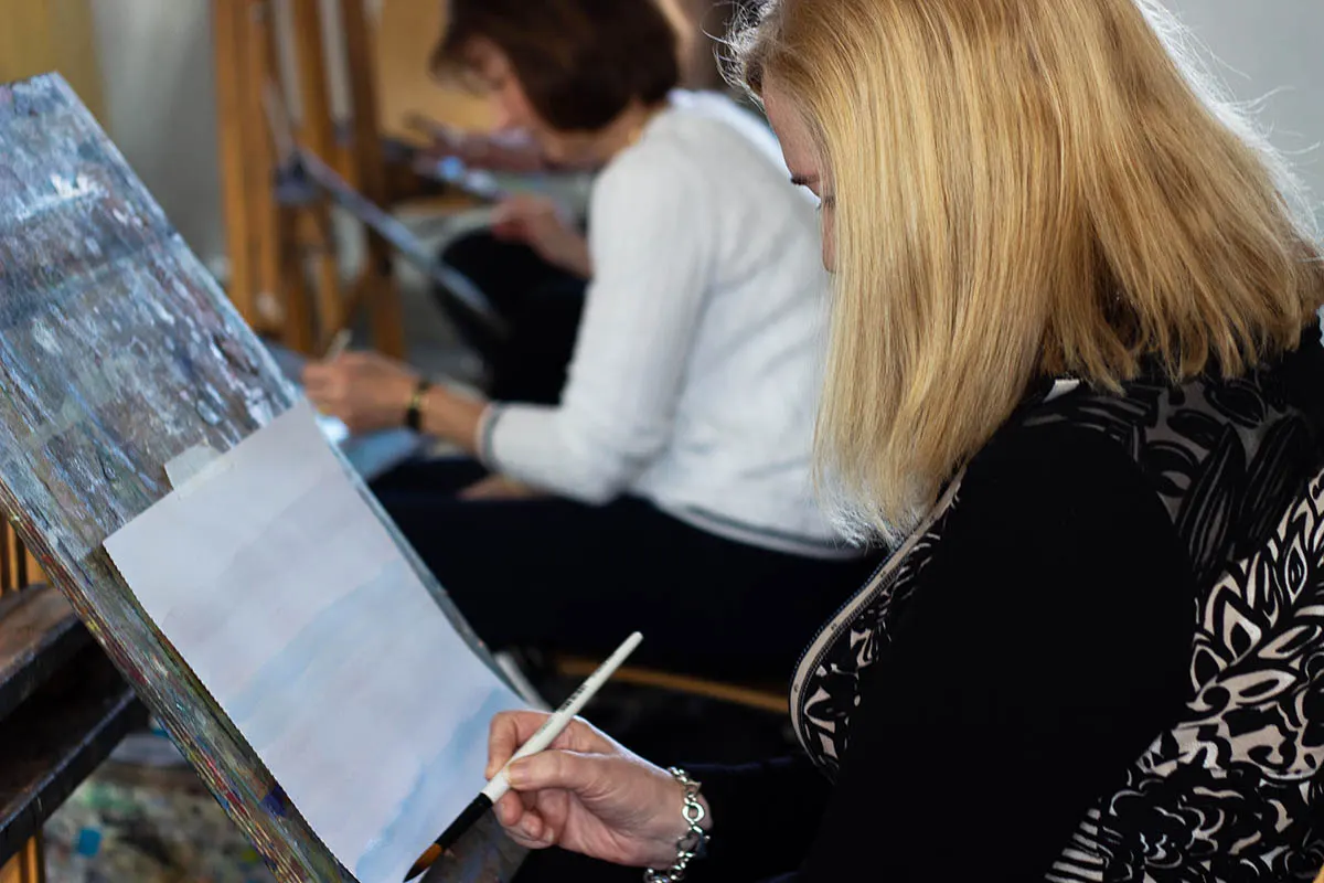 People painting or drawing on canvases during an art class or workshop session.