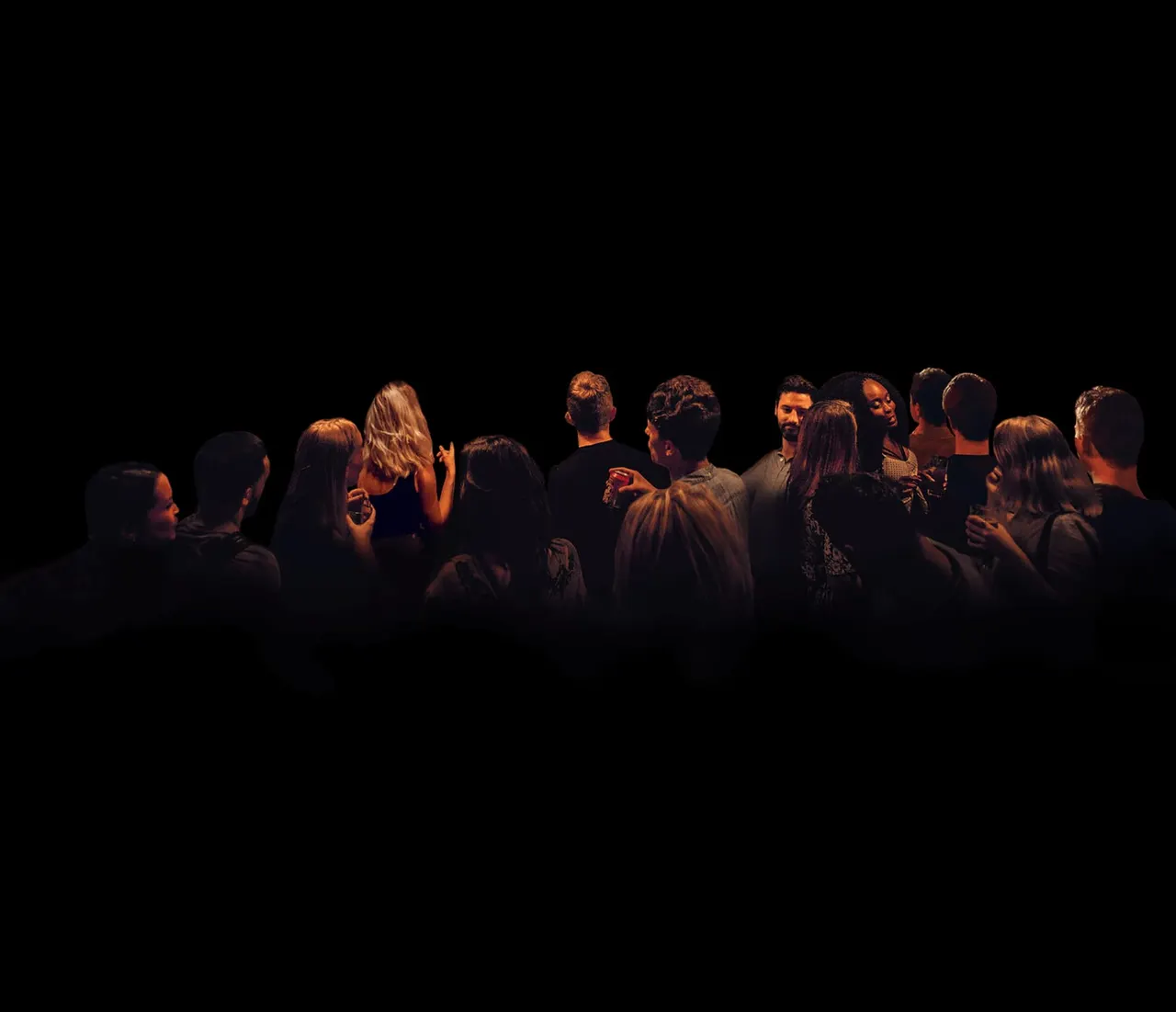 A group of people standing together on a darkly lit stage, engaged in conversation or performance.