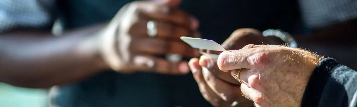 Close-up of hands holding a small knife during a woodcarving or whittling demonstration.