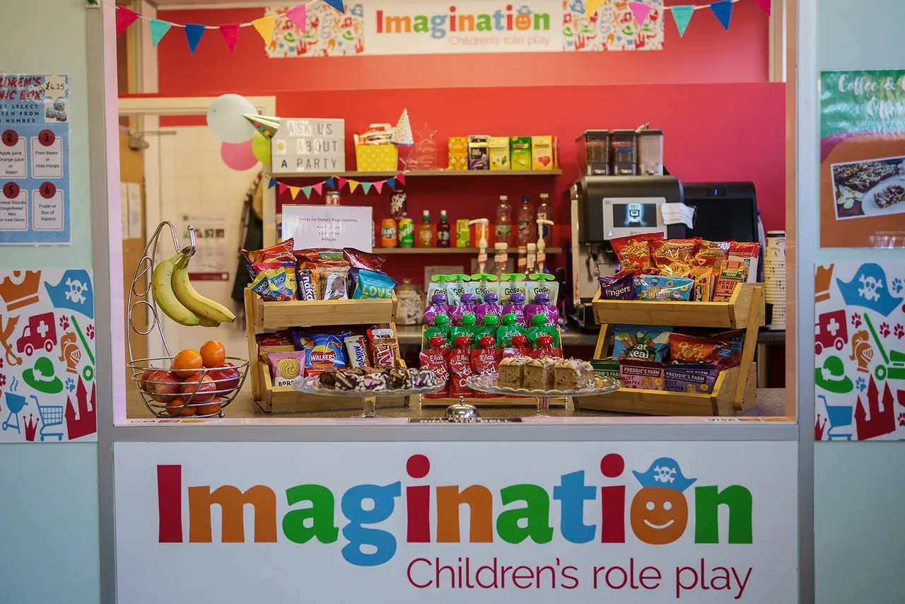 A colourful play shop counter displaying fresh fruit, snacks and packaged goods for children's role-play activities.