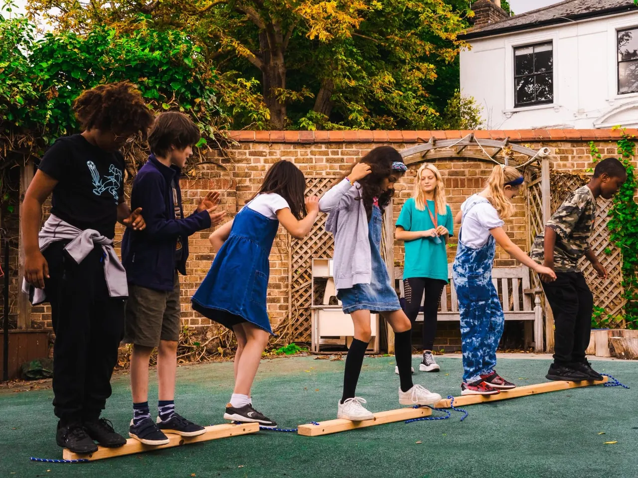 Children and adults playing mini golf on a garden course with a brick wall and ivy behind them.