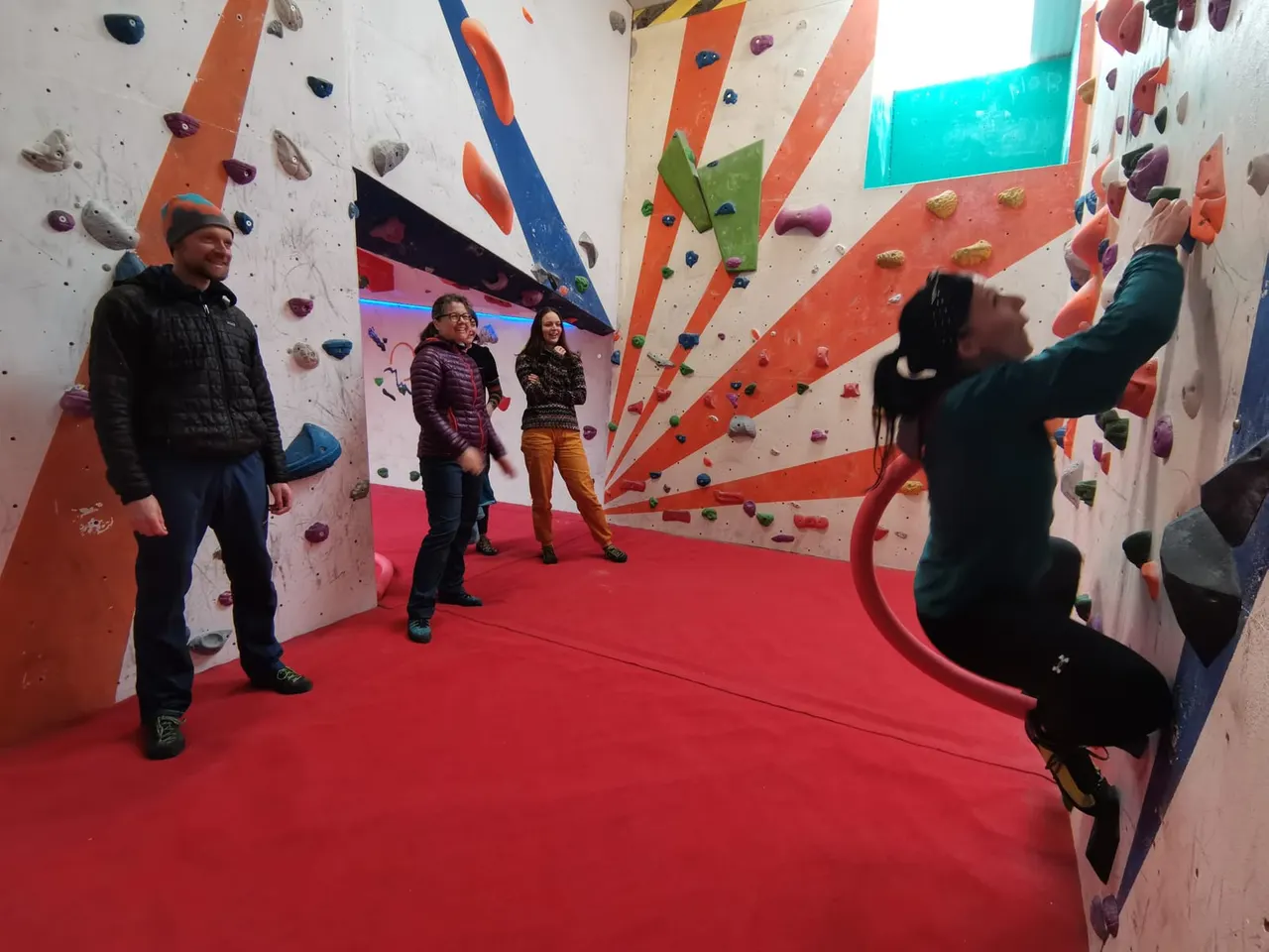 People climbing on coloured walls with handholds at an indoor climbing centre.