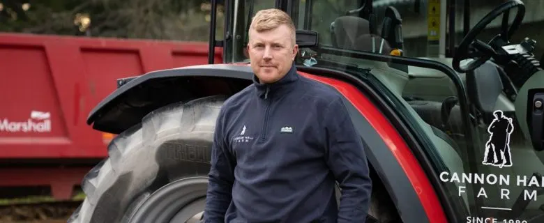 Man standing next to a large red farm tractor.