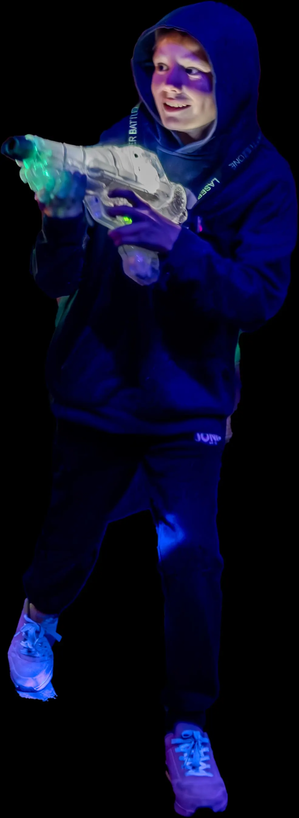 Child wearing blue hoodie and glowing gear holds a glowing laser tag gun against black background.