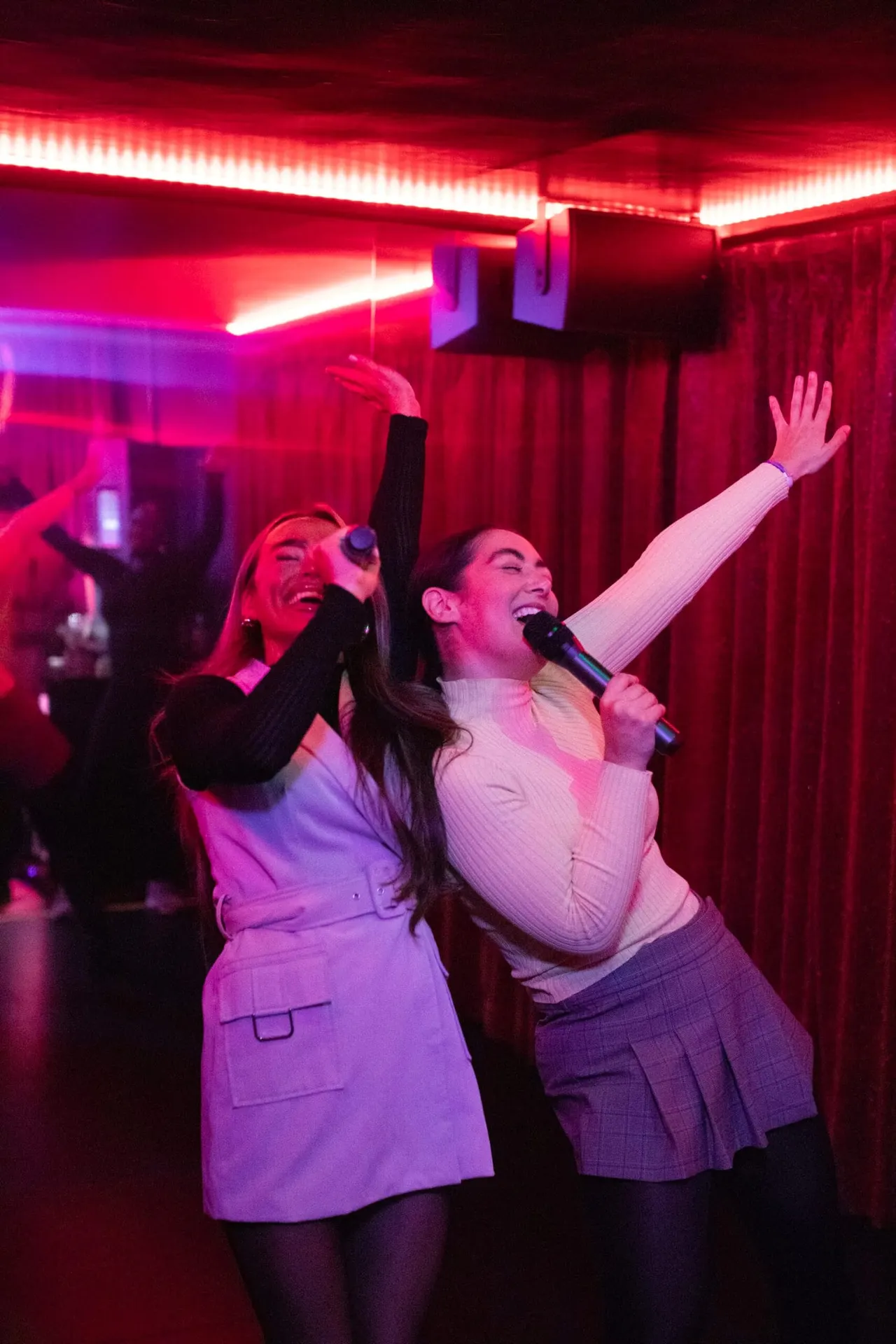 Two guests singing karaoke under red neon lights at Golf Fang Nottingham