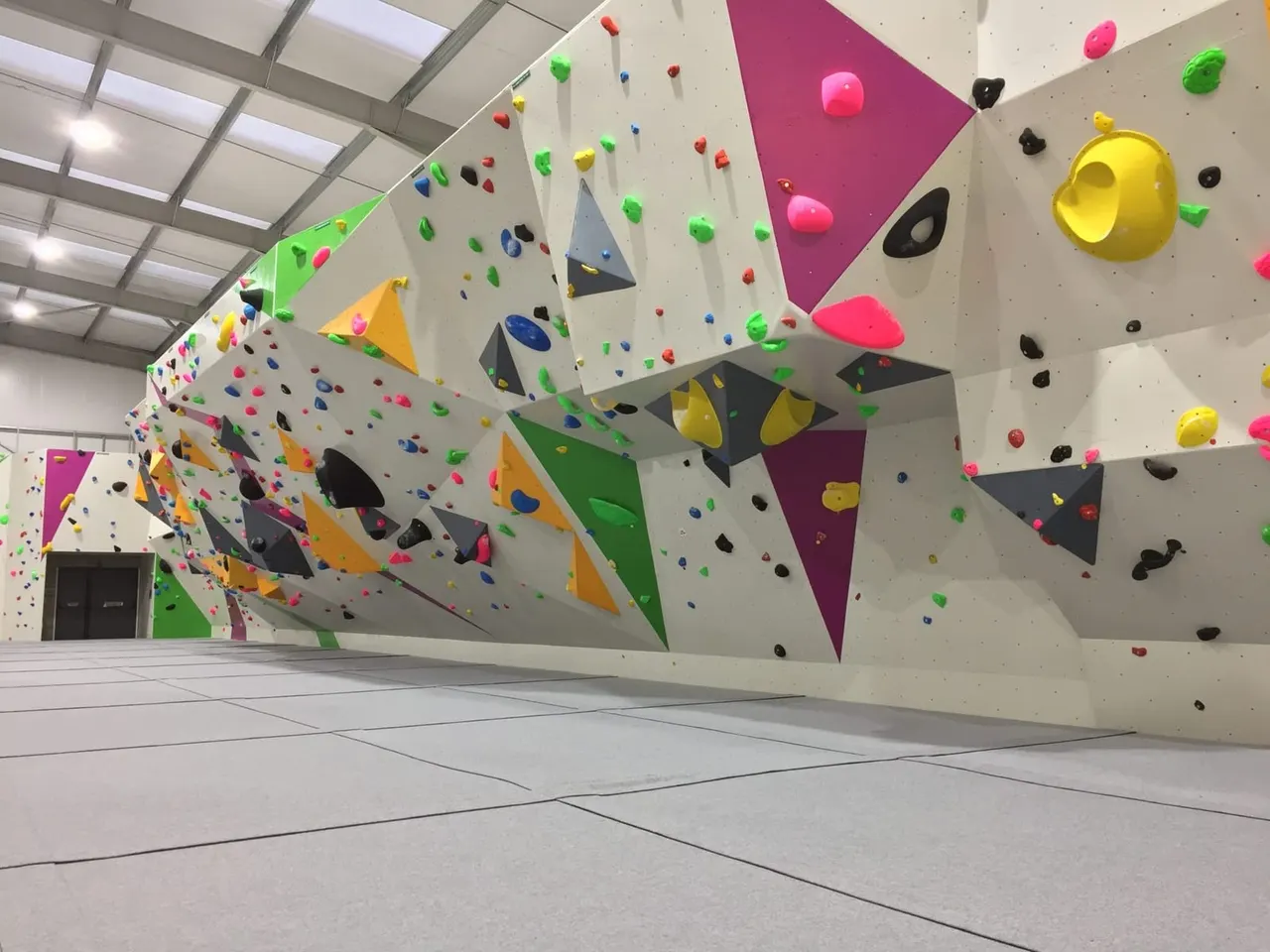 Indoor climbing wall with colourful holds and geometric features in a modern facility.