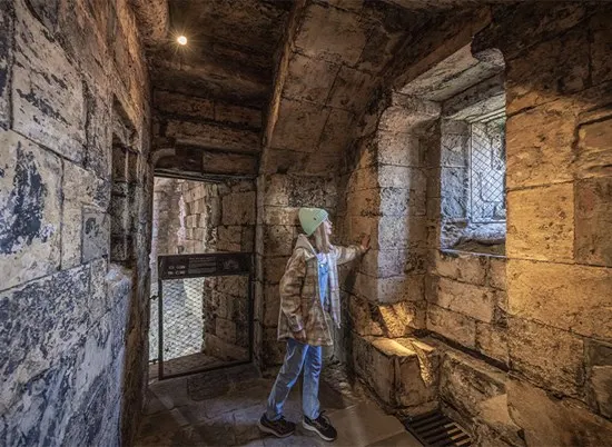 A visitor explores a stone-walled chamber inside a historic tower fortification.