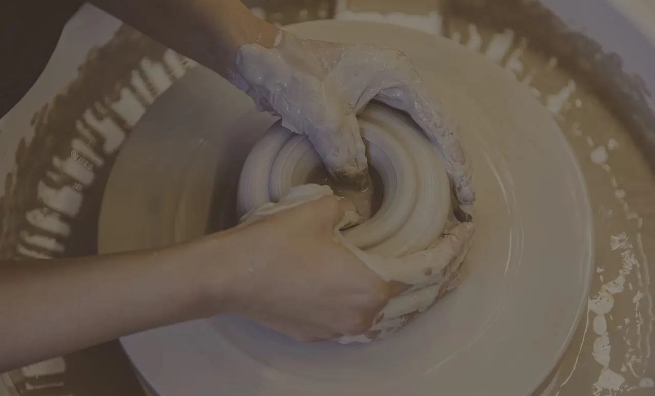 Hands shaping wet clay on a pottery wheel during a ceramics session.