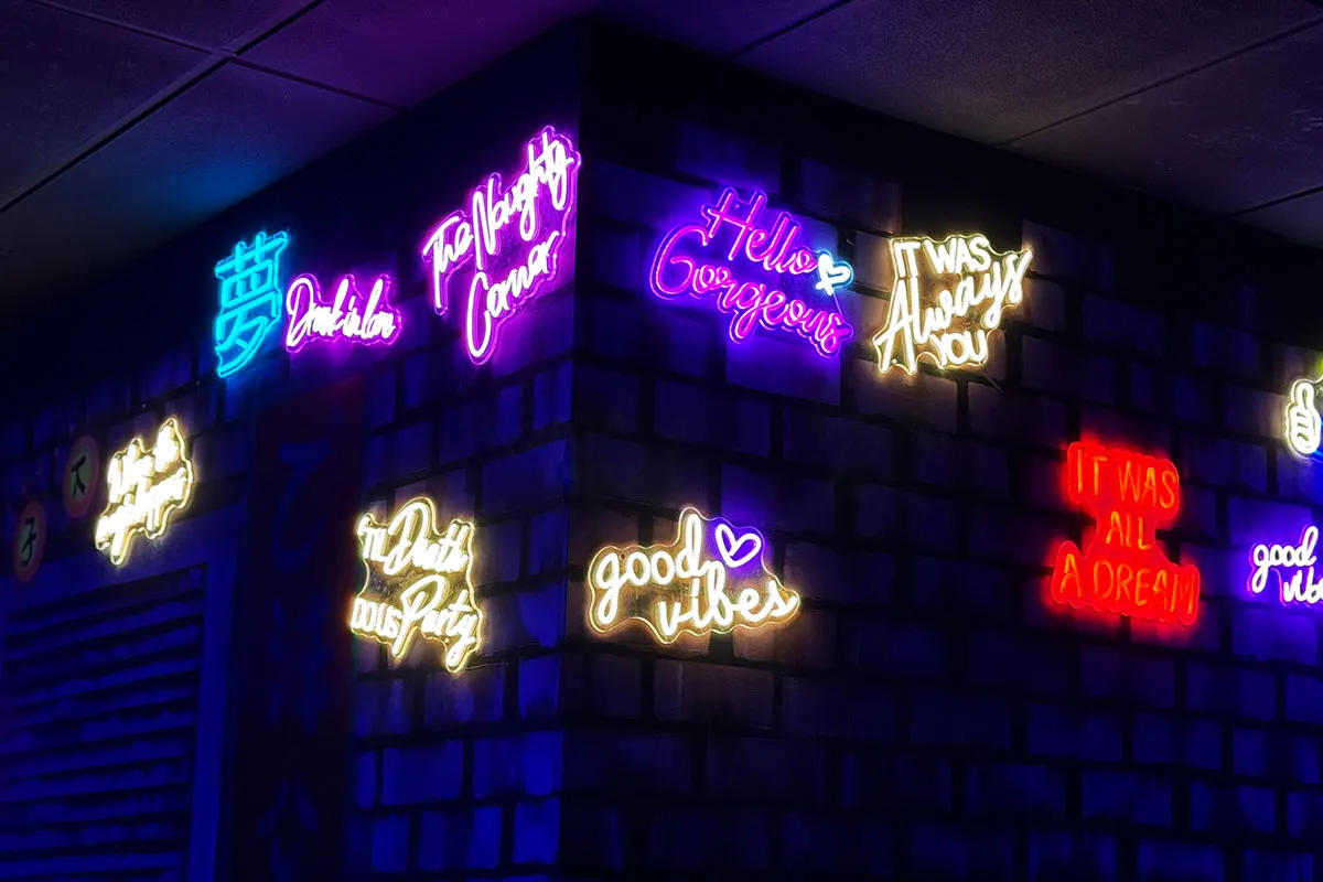 Colourful neon signs with inspirational messages and slogans displayed on a dark interior wall.