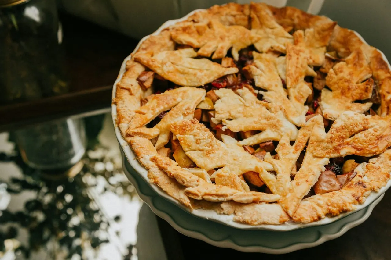 Freshly baked fruit pie with decorative pastry lattice top in a ceramic dish.