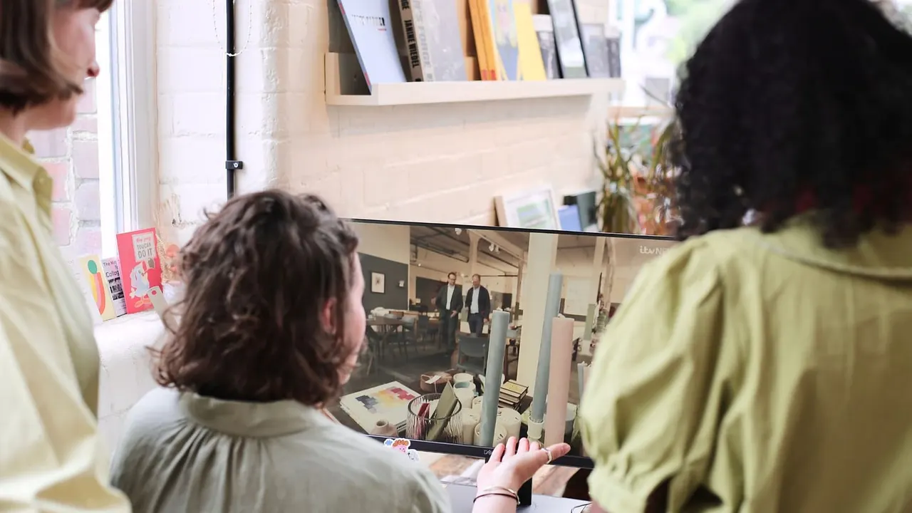 Three people in yellow shirts viewing a framed photograph displayed on a gallery wall.