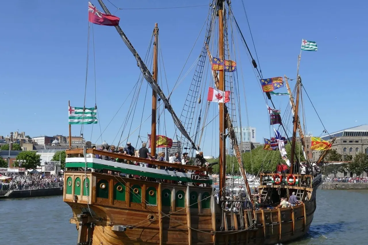 Replica medieval trading vessels moored on the River Avon with crowds gathered along the waterside.