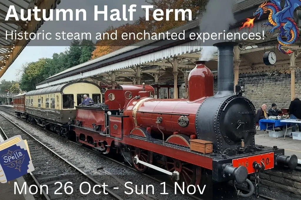 A red steam locomotive with cream and burgundy passenger carriages at a heritage railway station platform, with autumn trees visible beyond the covered station canopy.