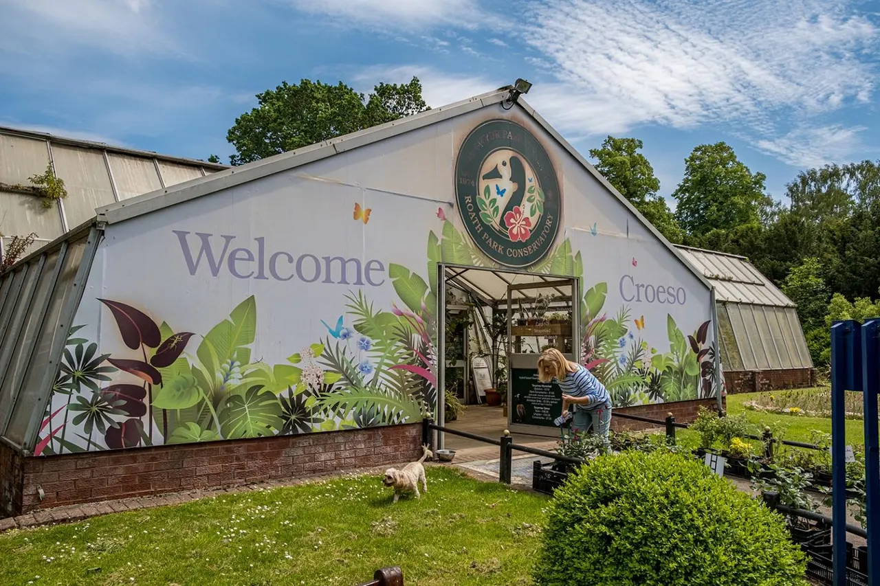 A child and small dog approach a welcome building decorated with floral murals at a park visitor centre.