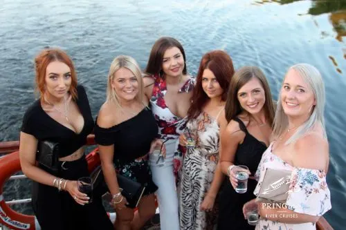 Six women posing together on a river cruise boat with water visible behind them.
