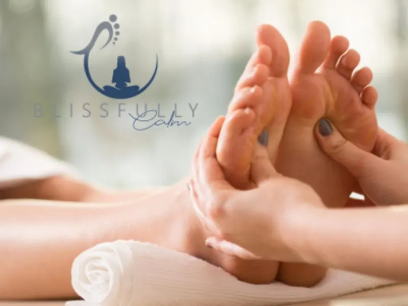 Therapist's hands performing a foot massage on a client during a wellness treatment session.