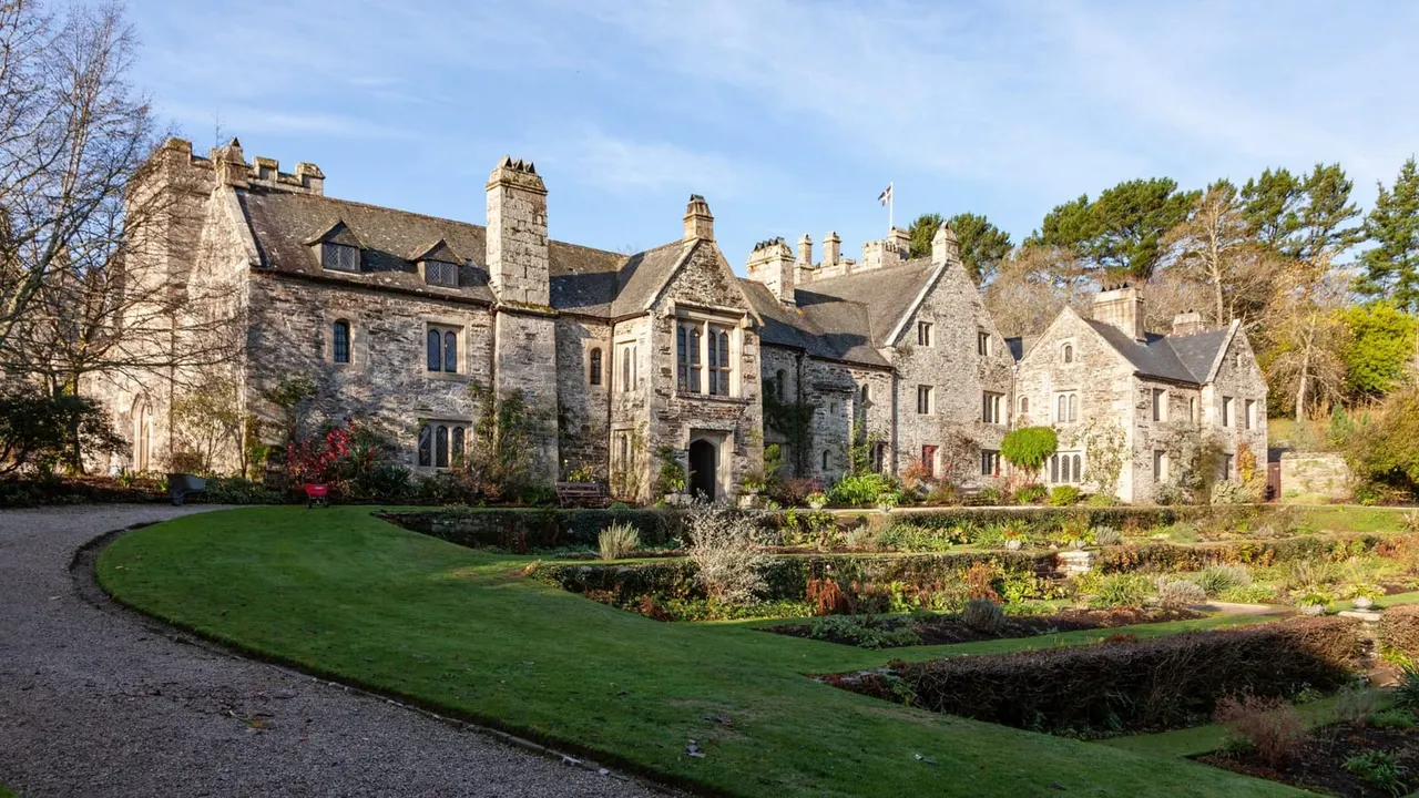 Historic stone manor house with manicured lawns and gardens in autumn.