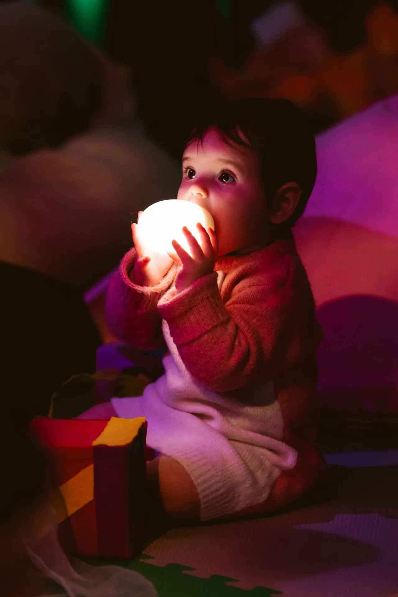 A toddler holding a softly glowing light in the Magical Garden sensory space