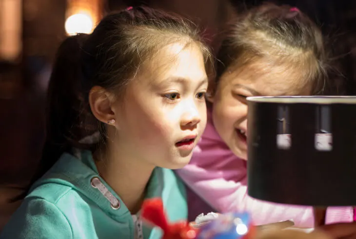Two children engaged with an interactive display or exhibit at an indoor venue.