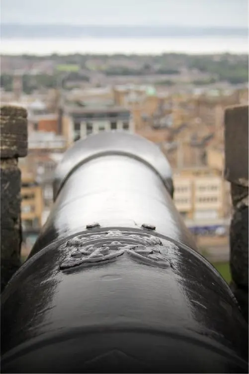 Canon pointing toward a town landscape from an elevated viewpoint.