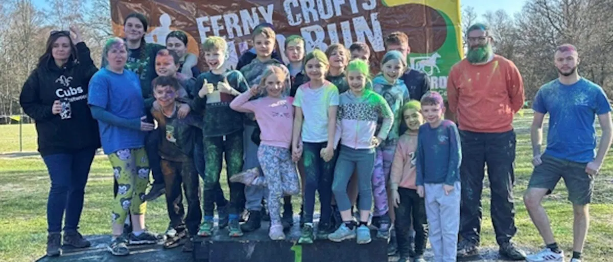 Large group of children and adults posing together outdoors at a scouts event in a park setting.
