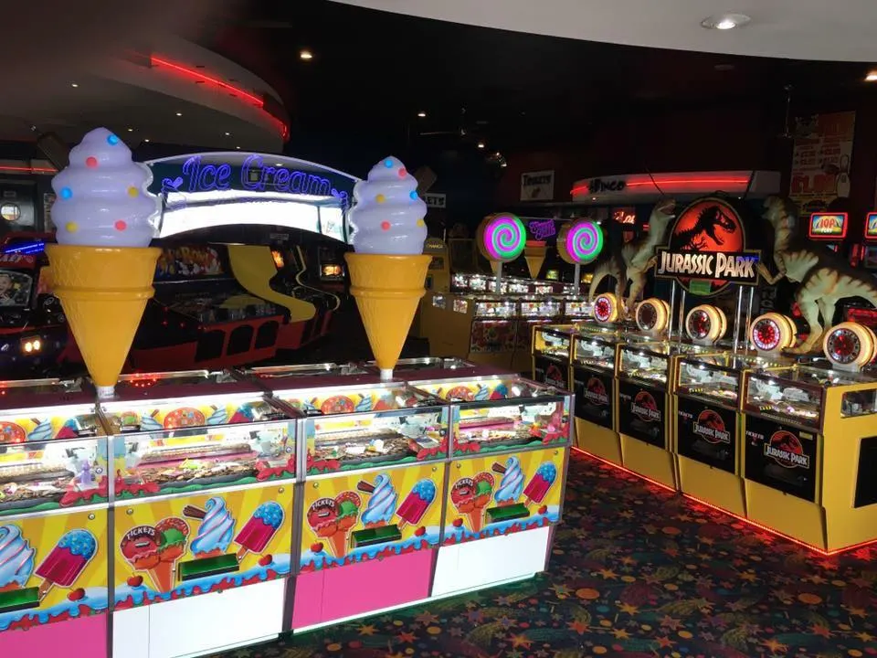 Arcade games and an ice cream themed ticket redemption machine in a dimly lit amusement arcade.